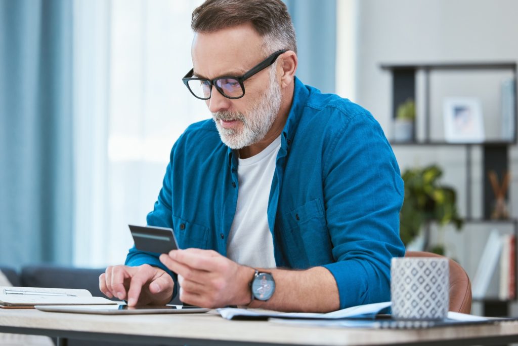 Man, tablet and online with card in home, customer and internet transaction on fintech for e commerce purchase. Payment, website and checking credit score